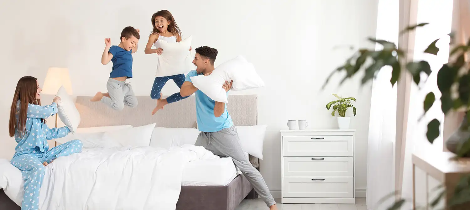 Family having a pillow fight on a bed - Keep your family safe from bed bugs with Seitz Brothers Pest Control in Tamaqua PA